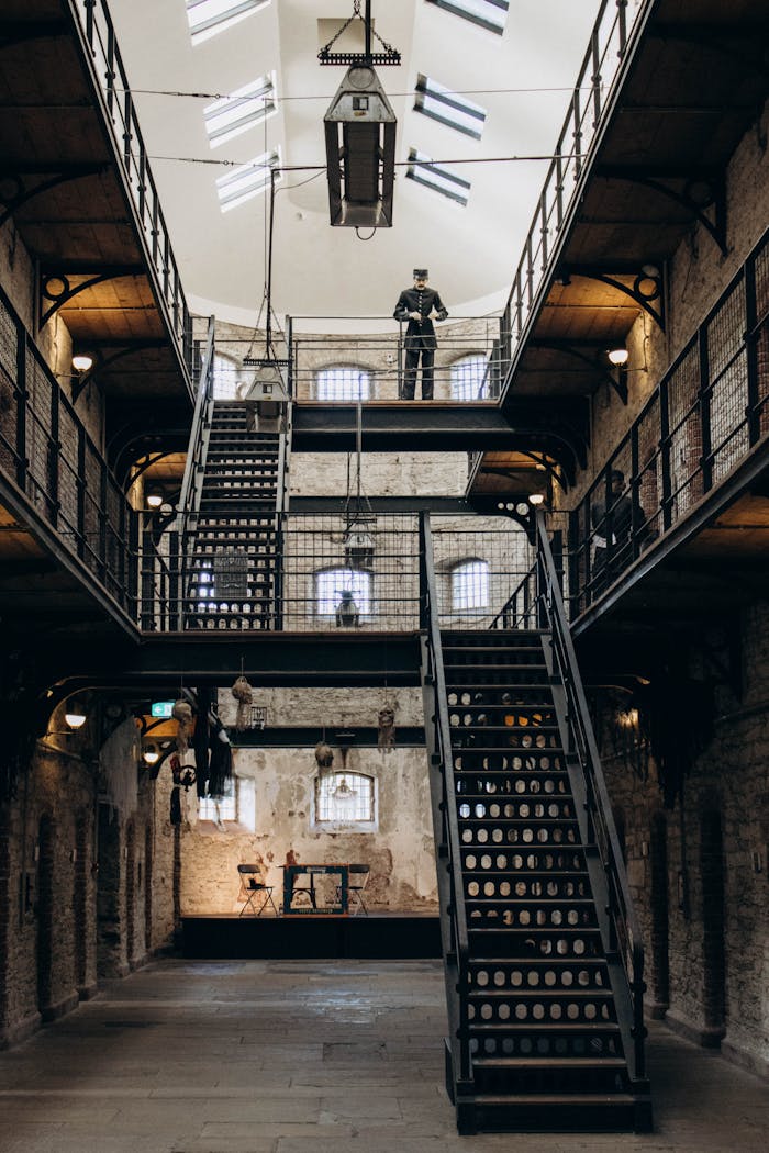 An atmospheric view of a historic prison interior featuring a guard on an upper level.